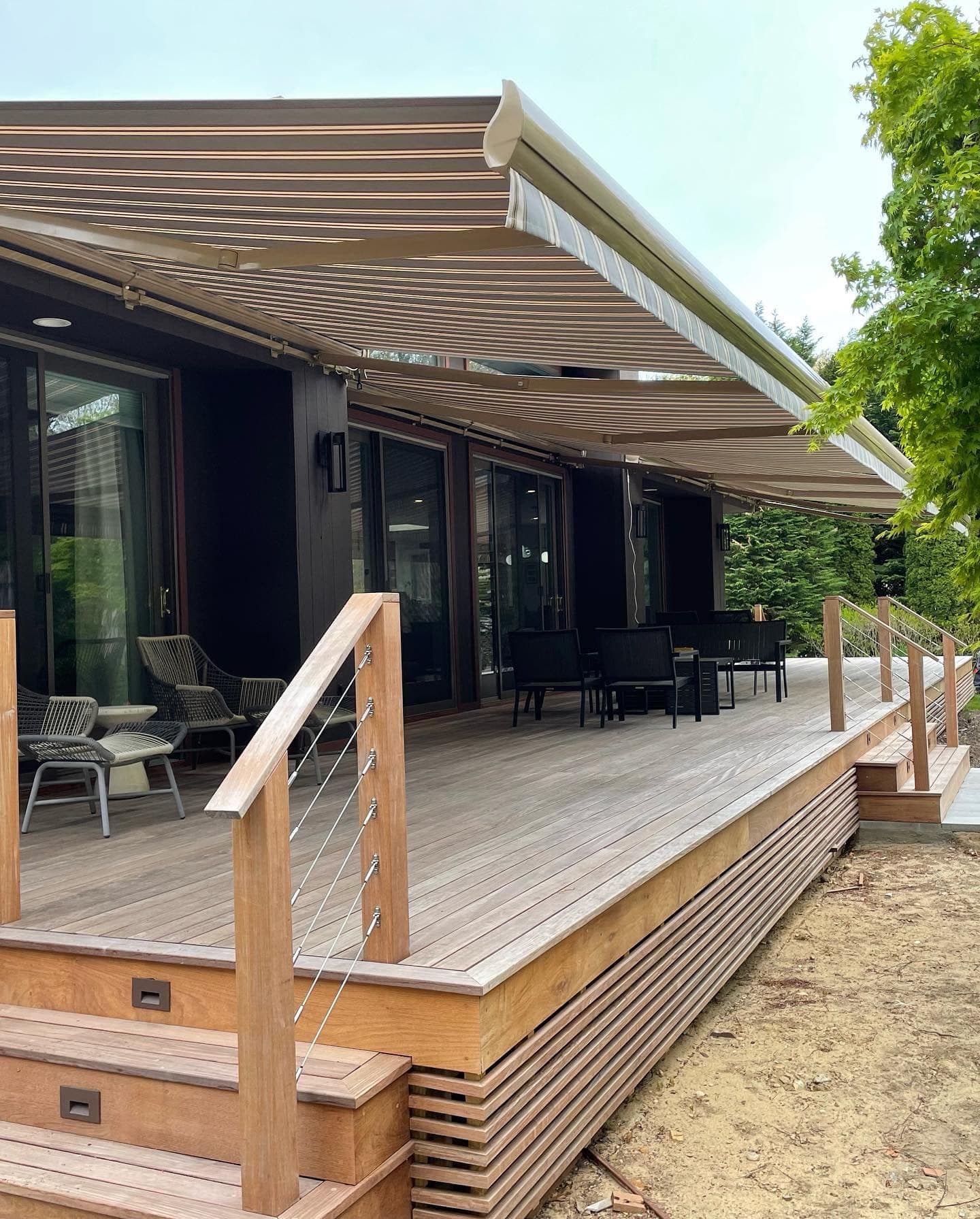 A striped retractable awning covers a brown back deck.