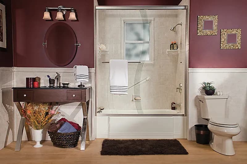 A burgundy bathroom with combination shower bathtub with sliding glass doors and off-white tile walls.