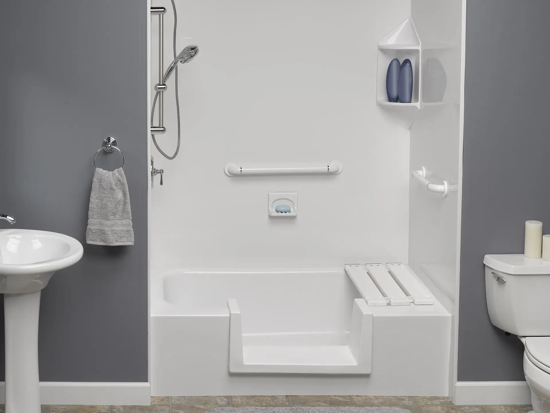 A gray bathroom with an accessible, low-threshold step-in shower with built-in bench seat and grab bars.