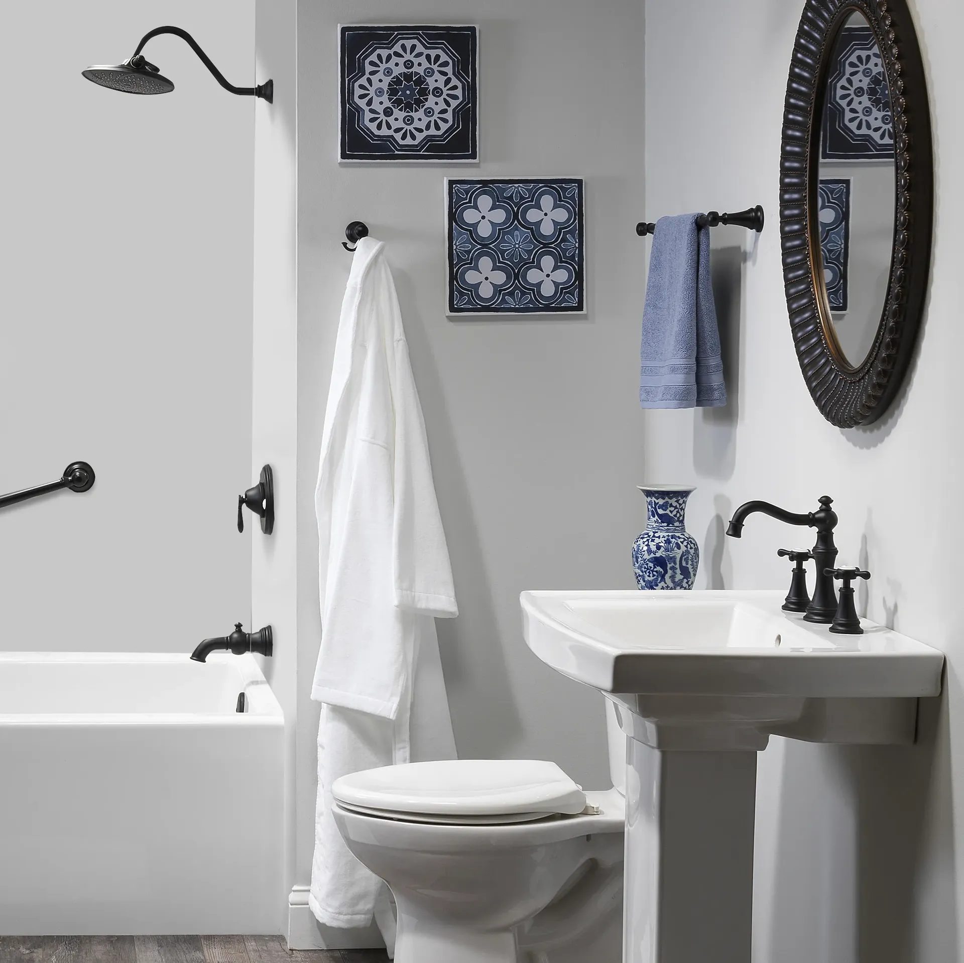 A white bathroom with combination shower bathtub and black fixtures and a robe hanging from the wall.