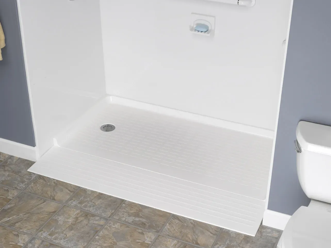 A close-up of a white, walk-in shower pan in a gray bathroom.