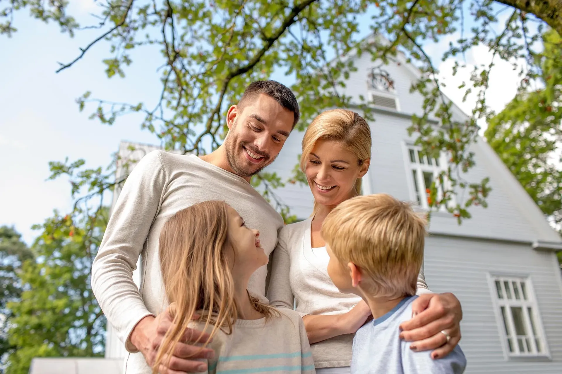 A family smiles at each other outside a house.