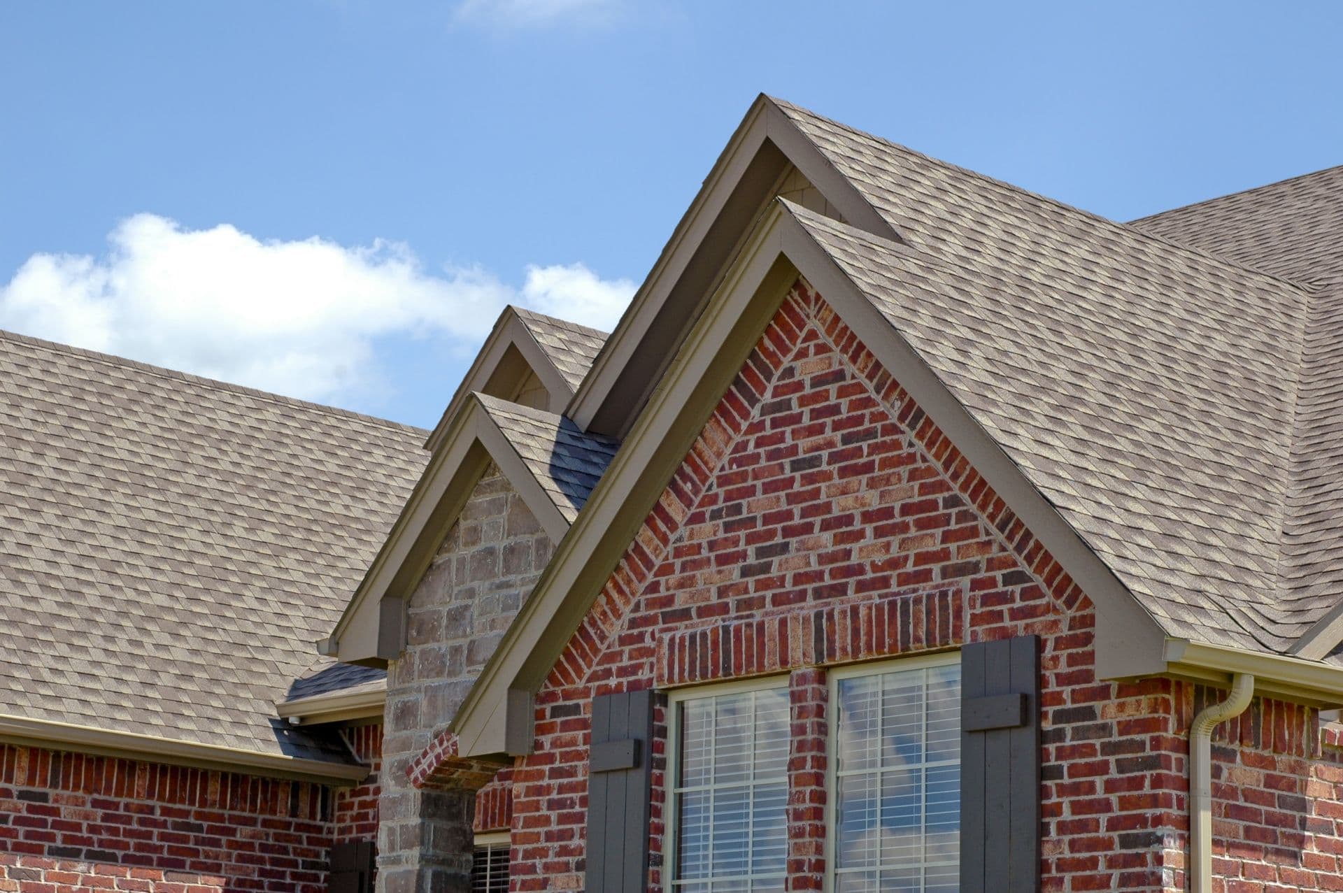 A red brick house with new gray roofing.