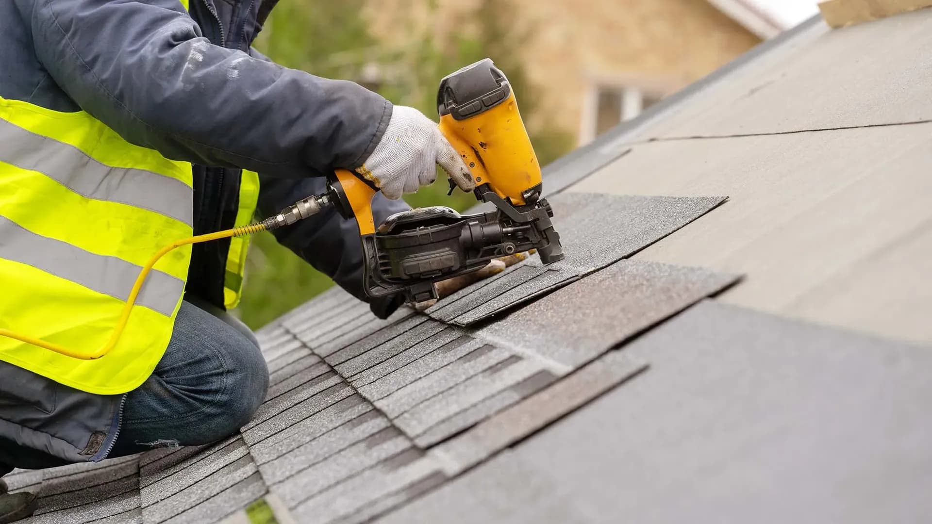 A worker installs roofing shingles.